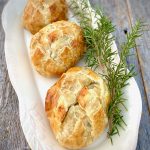 3 beef wellingotns with rosemary on a white platter