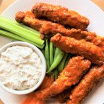 a plate of chicken tenders with buffalo sauce and dip