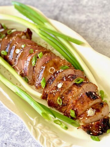 Asian marinated pork loin on a platter with scallions