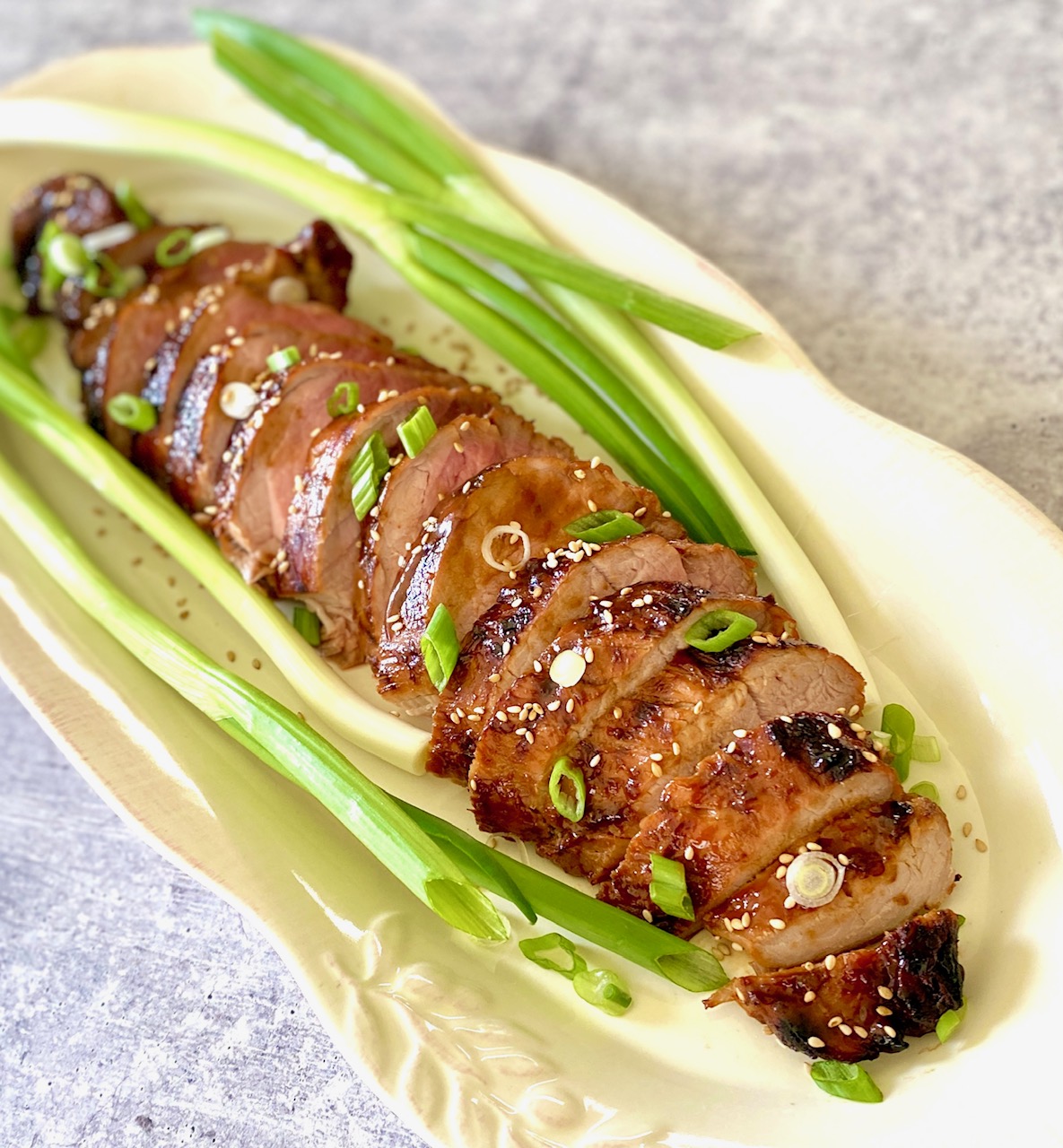Asian marinated pork loin on a platter with scallions