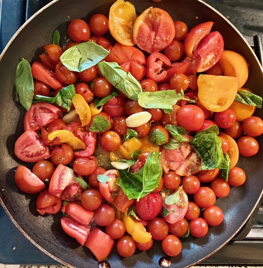 basil, tomatoes, garlic in a pan