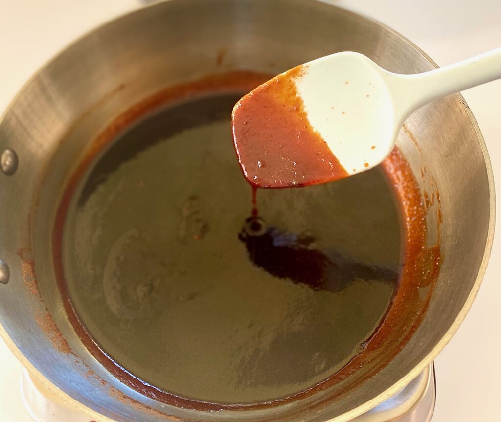 Sauce in a pan with blue spoon