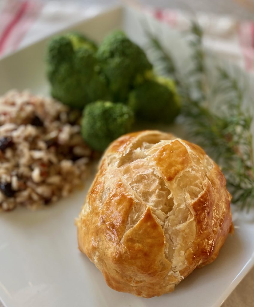 Beef Wellington with wild rice and broccoli on white plate