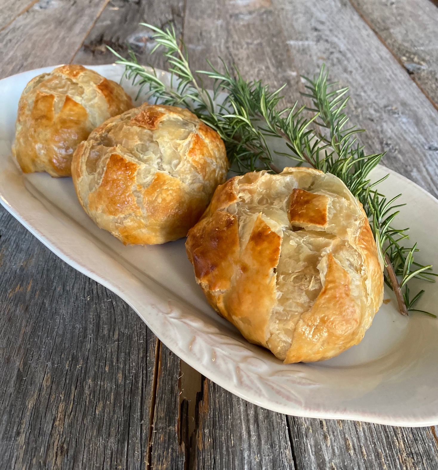 3 individual beef wellingtons on a white platter