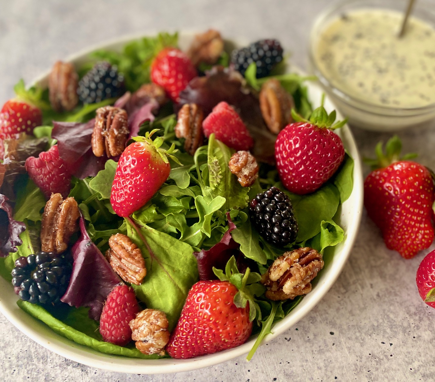 bowl of berry salad with bowl of dressing