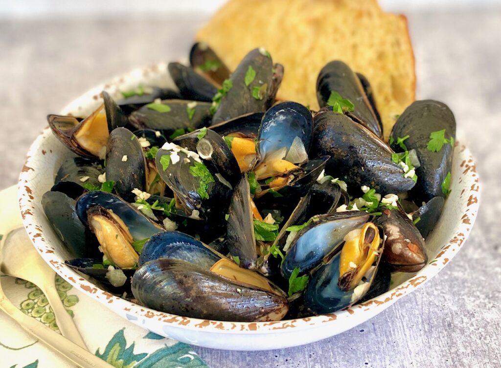 white bowl of garlic mussels and bread