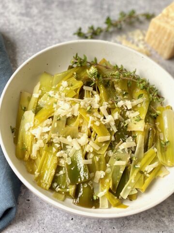 Braised leeks with parmesan cheese in white bowl