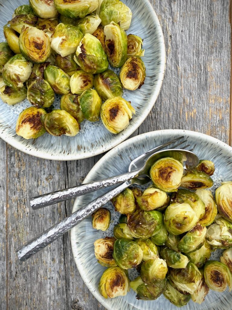 2 bowls of roasted Brussels sprouts with silverware