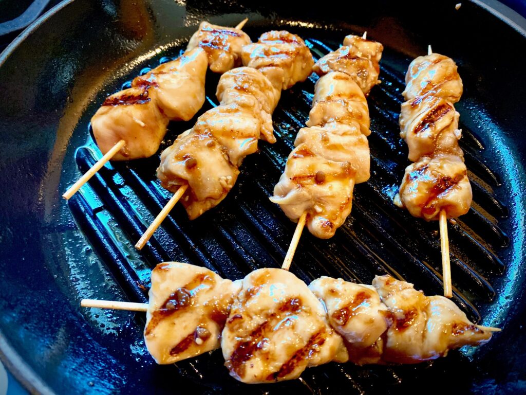 chicken skewers grilling on stove top pan