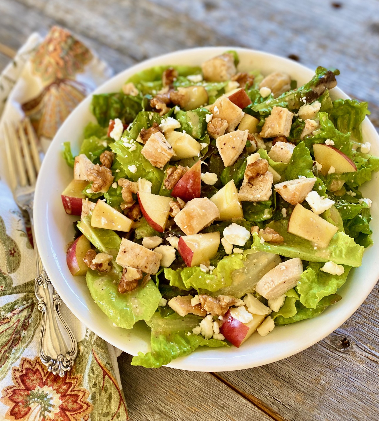 chicken and apple salad with nuts in white bowl
