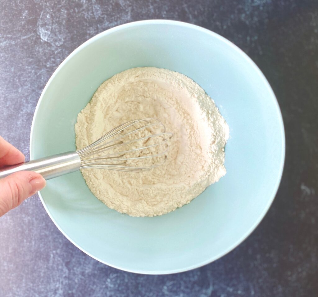 whisking flour in a blue bowl