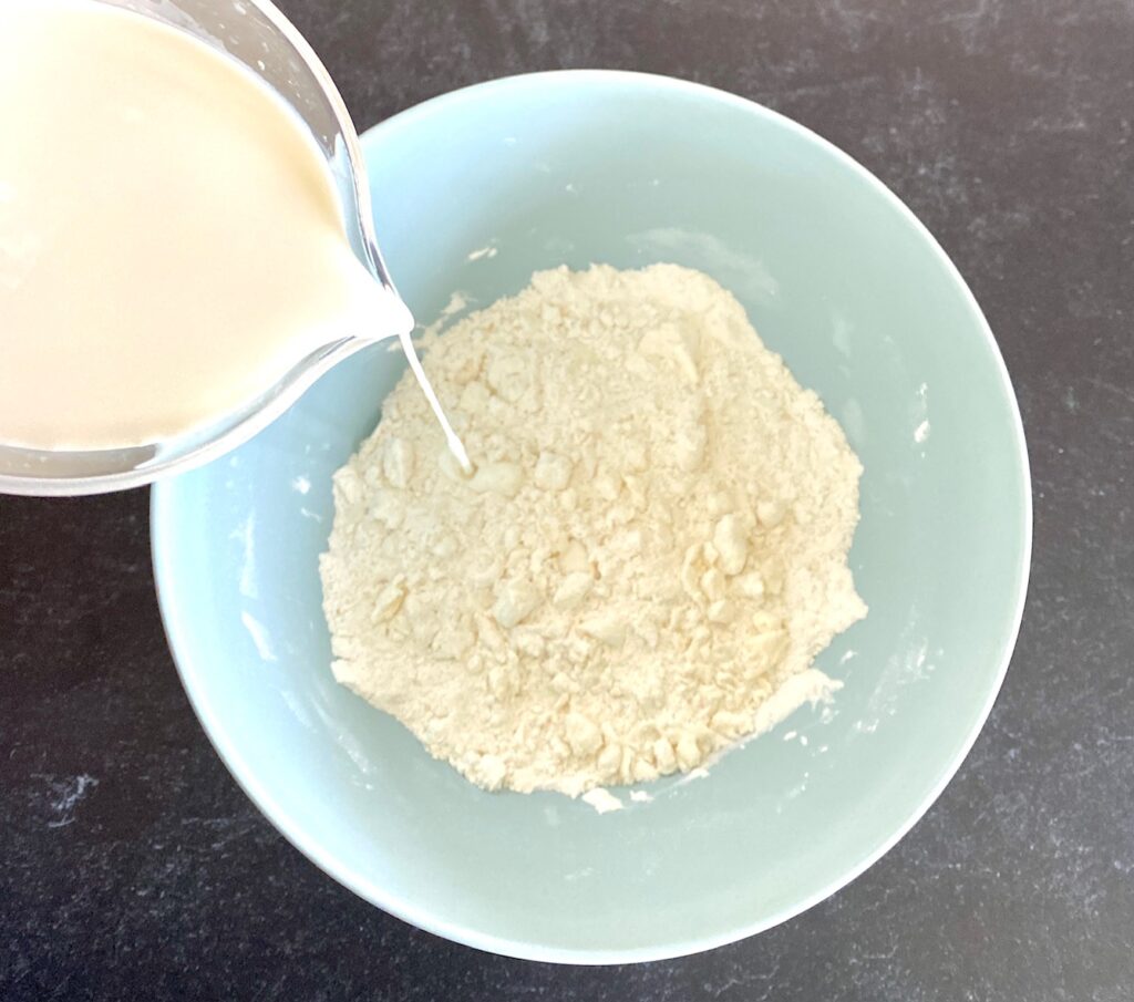 pouring cream into blue bowl of flour
