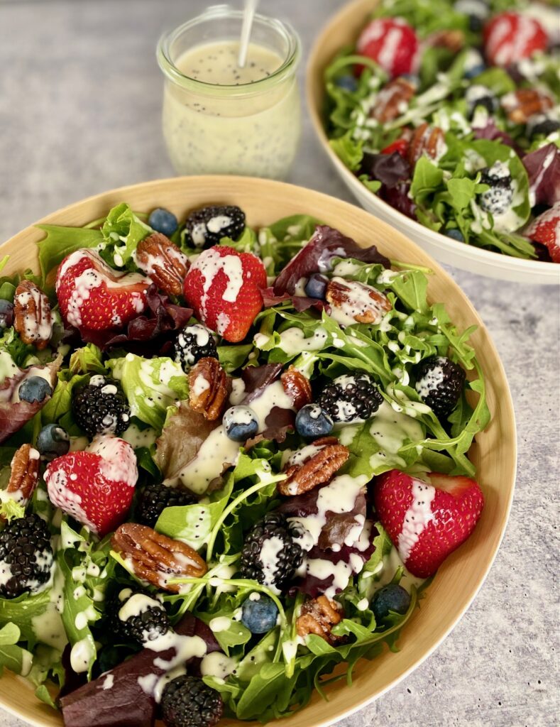 jar of dressing and 2 salads with fruit