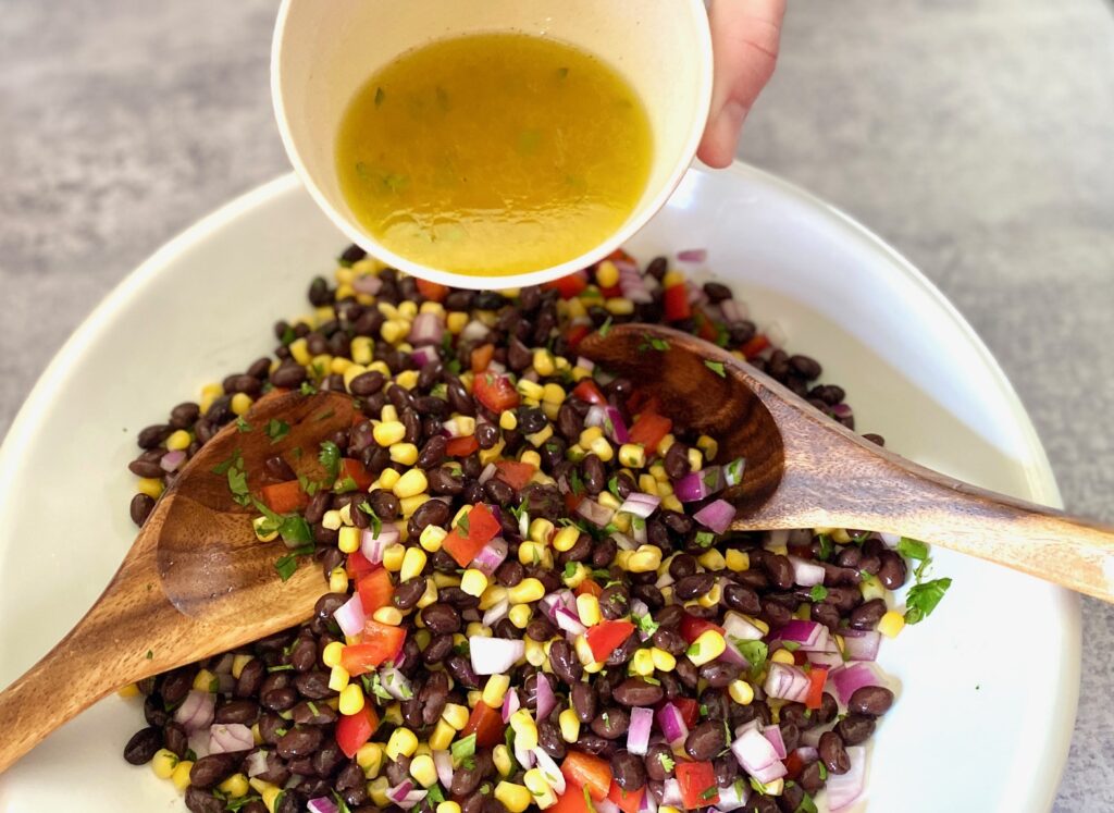 Pouring lemon dressing on a salad bowl