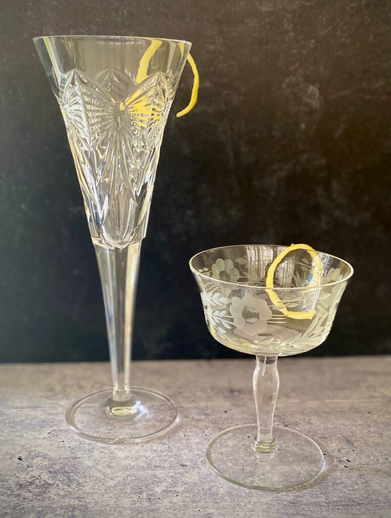 2 empty champagne cocktails with lemon twist garnish