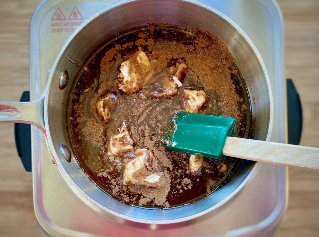 glaze for ham in a silver pan with green spatula