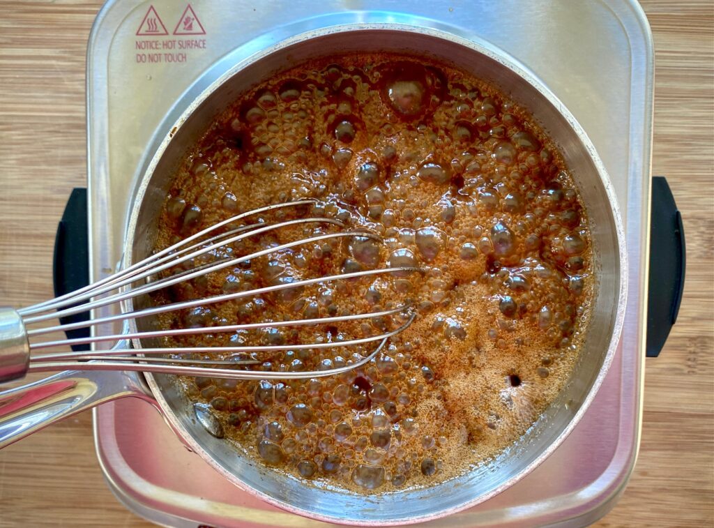glaze bubbling in a pan with a whisk