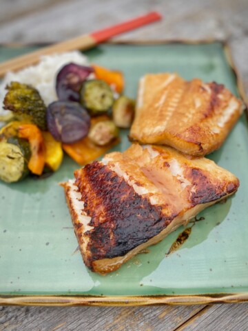 miso glazed sea bass on green plate with vegetables
