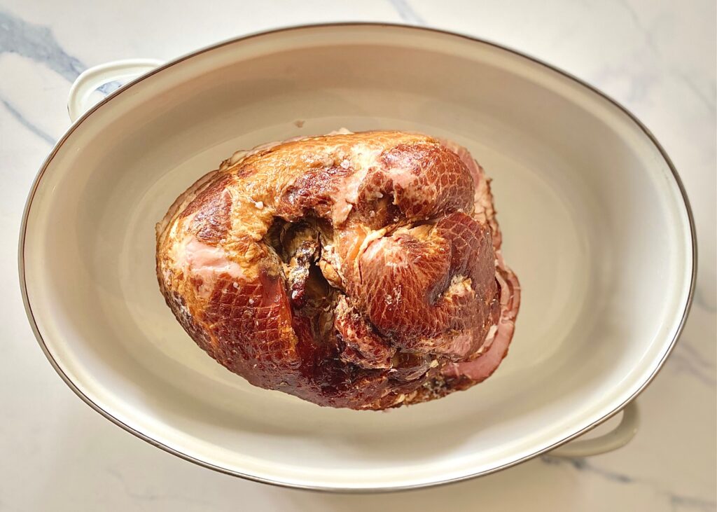 ham in a white roasting pan 
