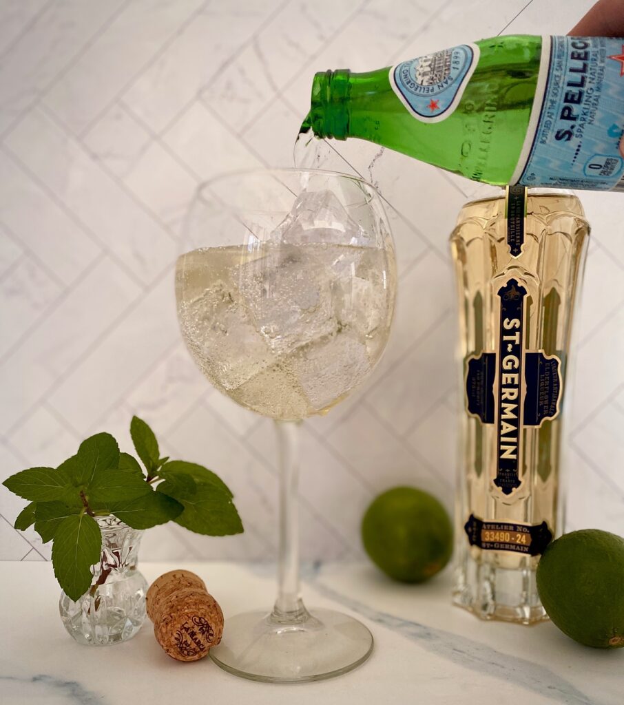pouring sparkling water into a Hugo spritz