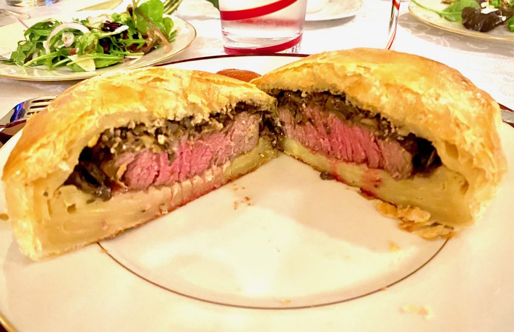 Beef wellington cut in half on a white plate