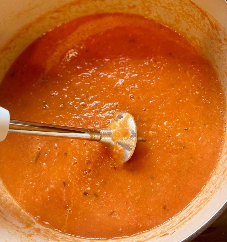 Immersion blender in a pot with marinara sauce