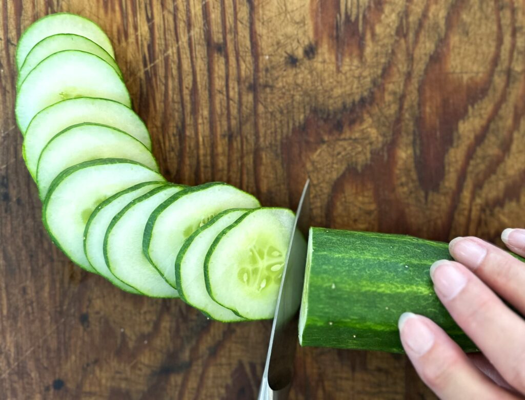 Slicing a cucumber on a wooden board