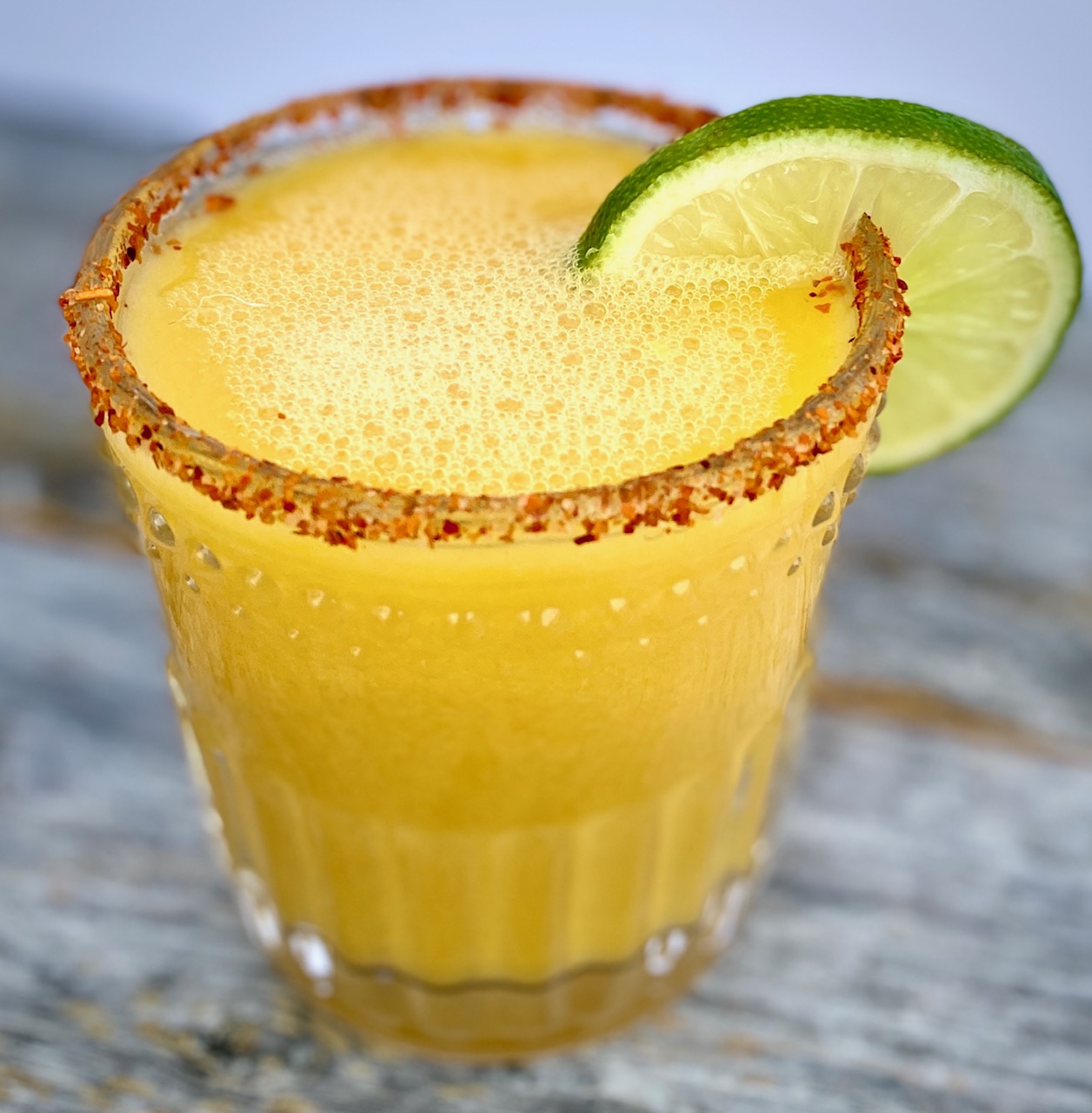 1 mango margarita with a lime and chiili on rim