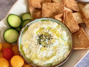 platter of tzatiki with tomatoes, crackers.
