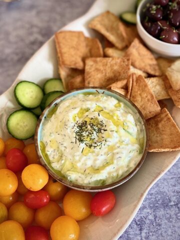 platter of tzatiki with tomatoes, crackers.