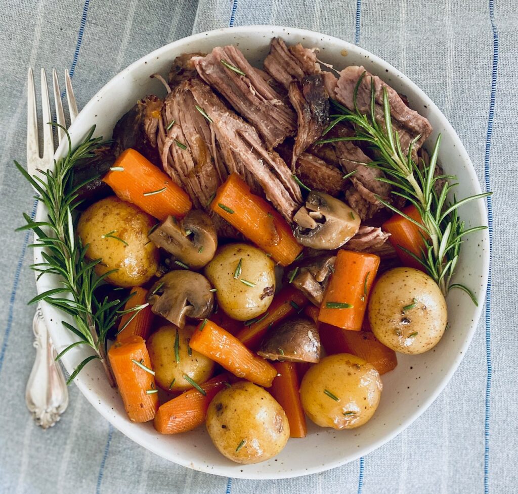 Bowl of pot roast with vegetables and rosemary