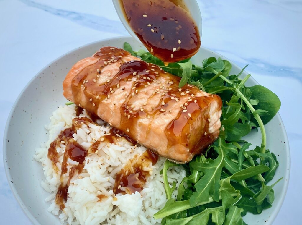 pouring teriyaki on salmon