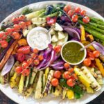 a platter of roasted vegetables with dipping sauces