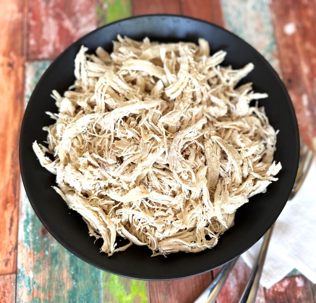a black bowl with cooked chicken that is shredded