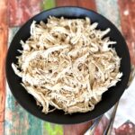a black bowl with cooked chicken that is shredded