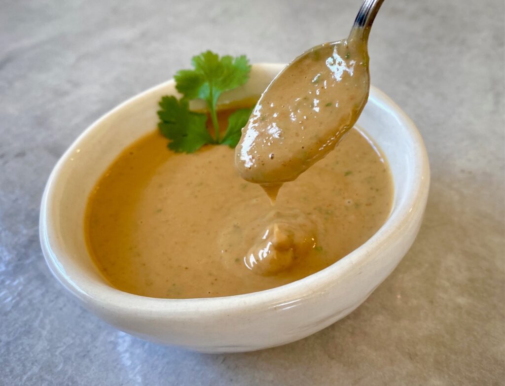 Spicy peanut sauce in a white bowl with a spoon