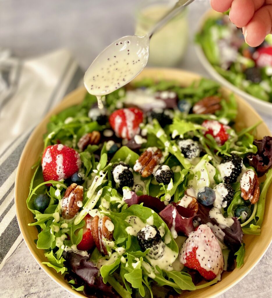 spoon drizzling dressing on salad