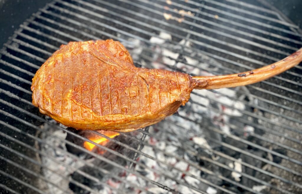 Tomahawk steak cooking on a grill