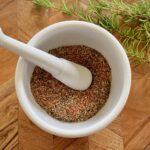 wooden board with white mortar and pestle and spices.