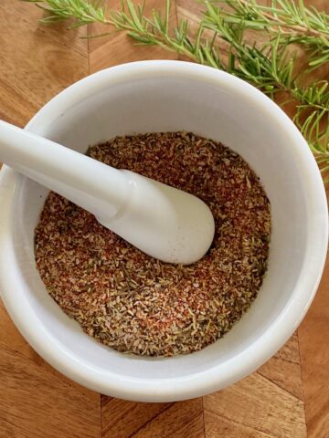 wooden board with white mortar and pestle and spices.