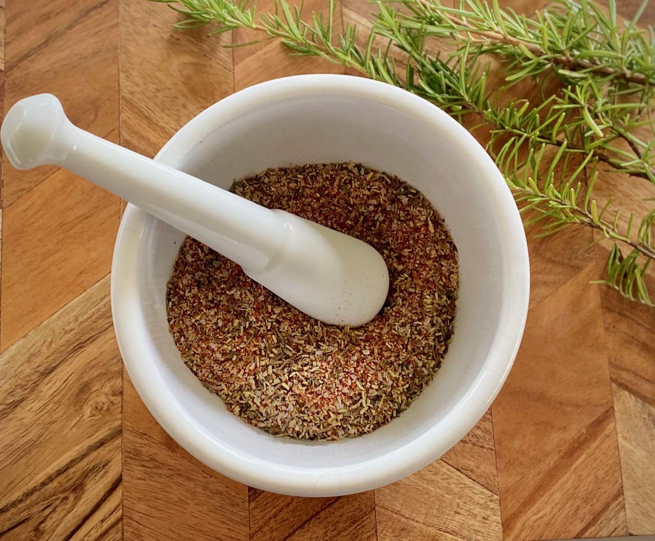 wooden board with white mortar and pestle and spices.
