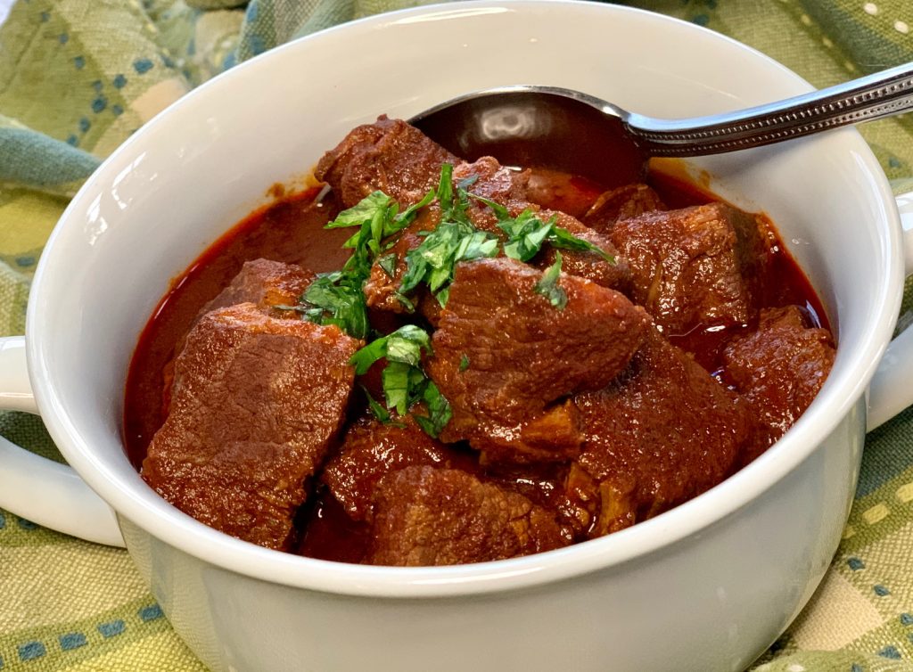 Chile Colorado in white bowl with parsley garnish