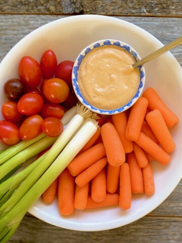 carrots, tomato and scallions in white bowl with cup of southwest ranch dressing