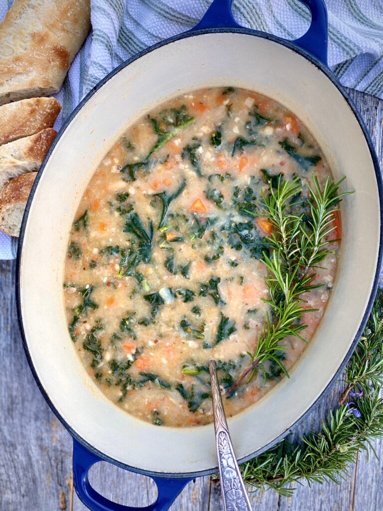 soup in a large pot with rosemary, kale and white beans