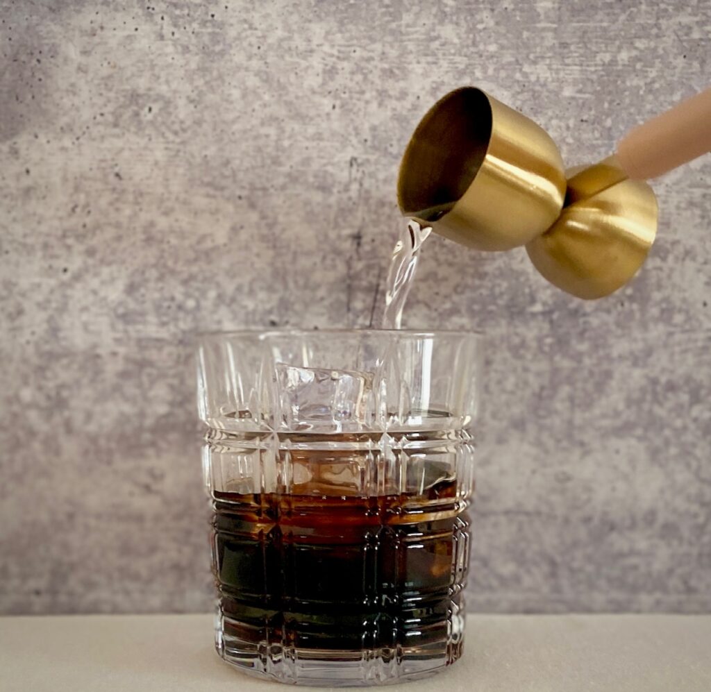 pouring vodka into kahlua in glass