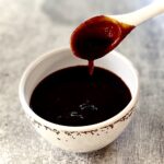 white spoon dripping sauce into bowl