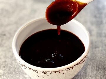 white spoon dripping sauce into bowl