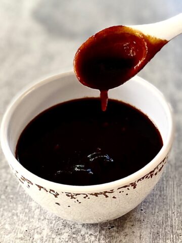 white spoon dripping sauce into bowl