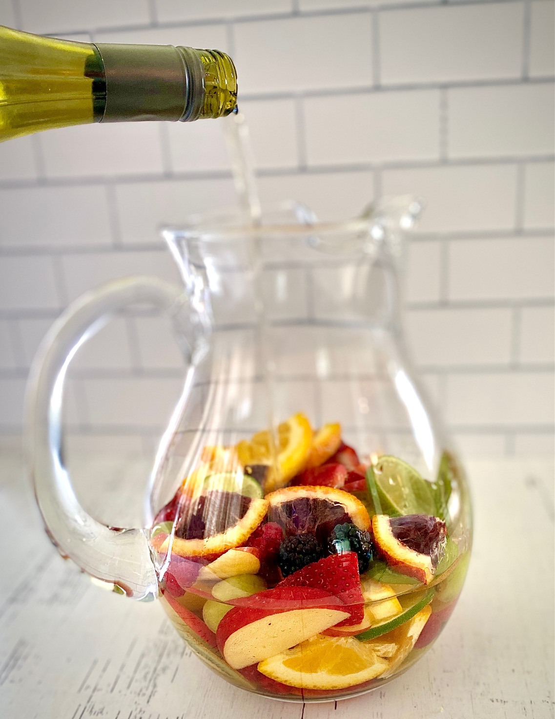 Wine pouring into pitcher of fruit