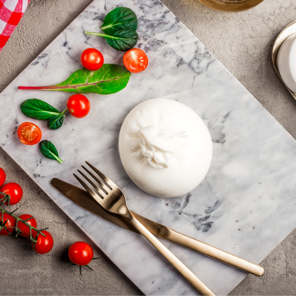 a ball of burrata with tomatoes on a piece of marble